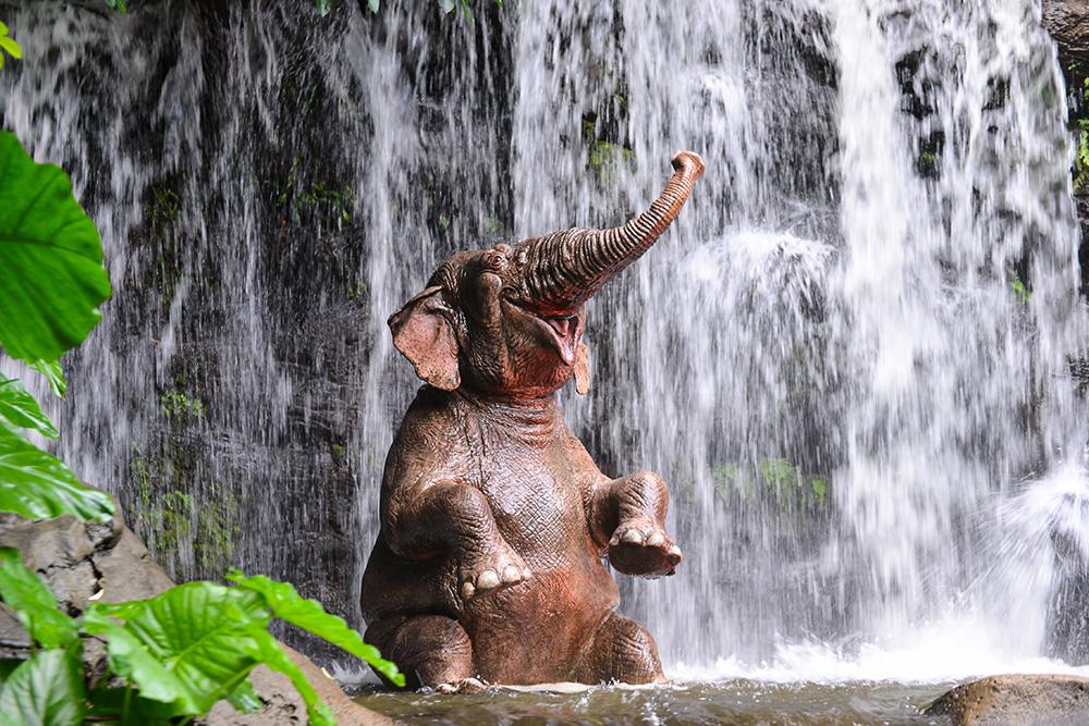 Fototapete Elefant duscht unter einem Wasserfall