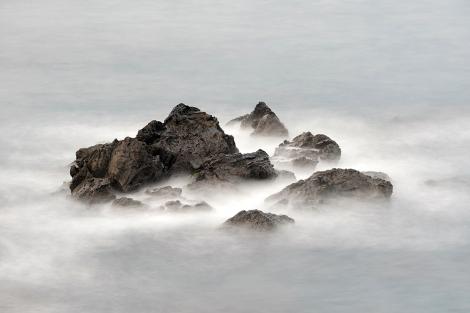Fototapete Felsen ragen aus dunstigem Wasser